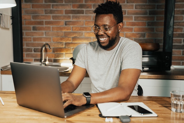 a person smiling and typing at their laptop